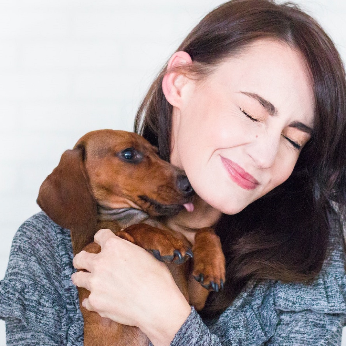 woman-holding-dachshund-dog-up-to-her-chin